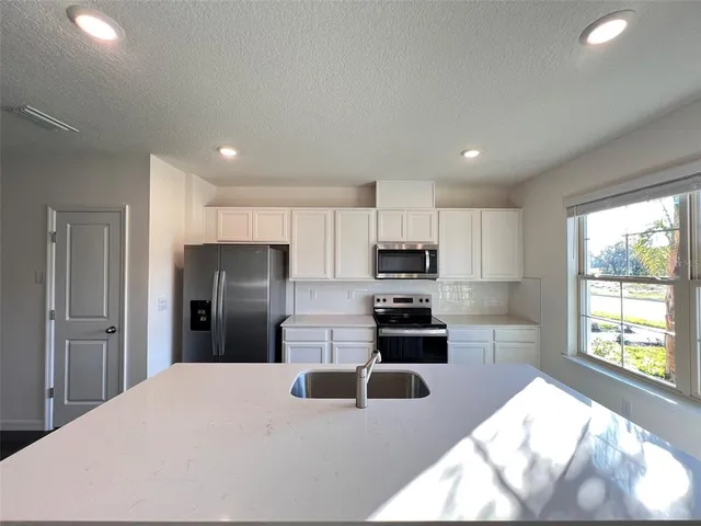 a kitchen with stainless steel appliances kitchen island granite countertop a refrigerator and a sink