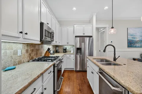 a kitchen with a sink a counter top space and living room view