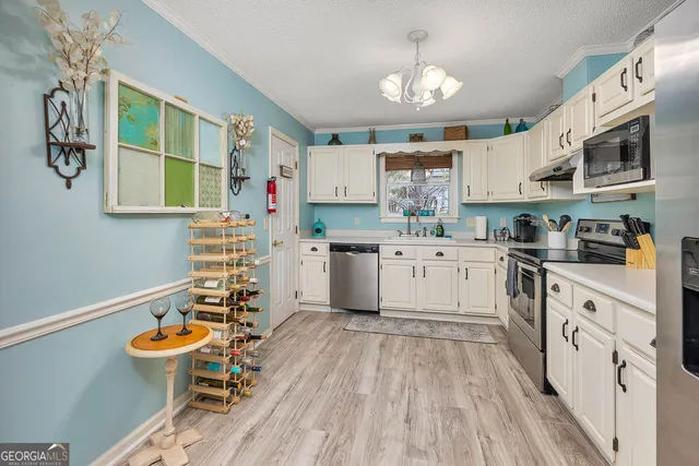 a kitchen with stainless steel appliances a white stove top oven a sink dishwasher and white cabinets with wooden floor