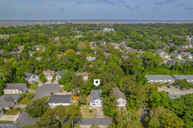 an aerial view of residential houses with outdoor space and trees all around