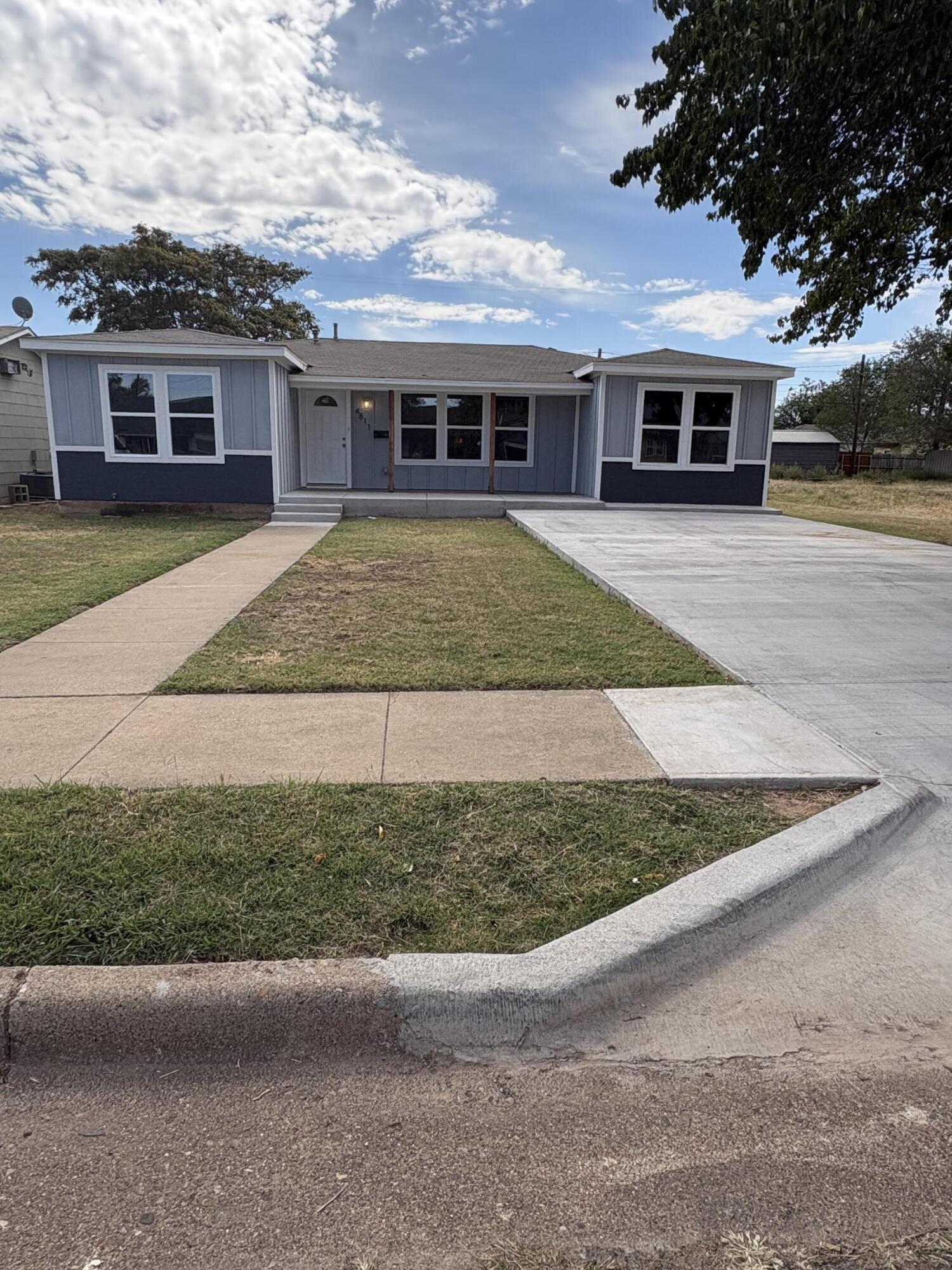 a view of a white house next to a yard with large trees