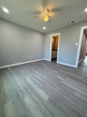 an empty room with wooden floor and a ceiling fan
