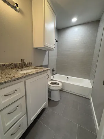 a bathroom with a granite countertop sink a toilet and bathtub