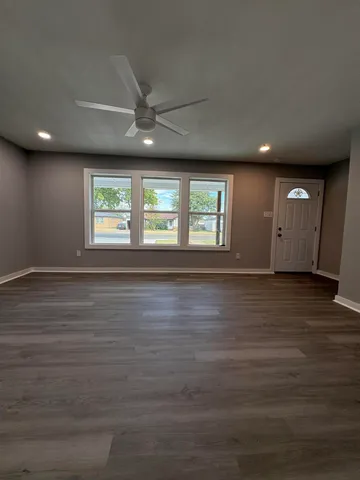 an empty room with wooden floor and windows