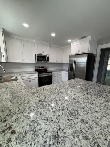 a kitchen with kitchen island granite countertop a refrigerator stove top oven and sink