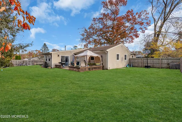 a view of a white house in front of a big yard with large trees