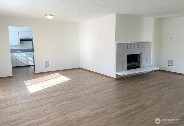 a view of empty room with wooden floor and fireplace