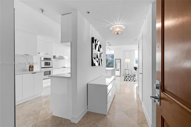 a living room with stainless steel appliances furniture a chandelier and a view of kitchen