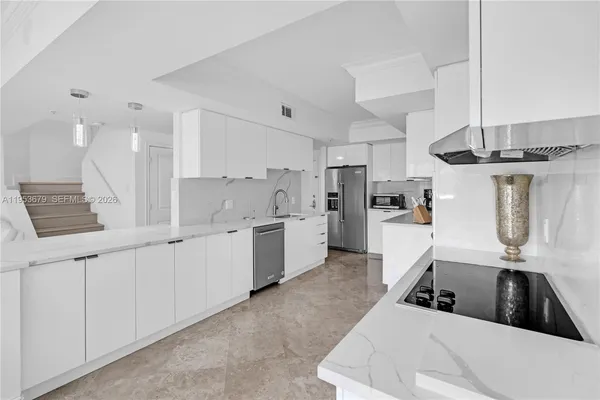a kitchen with white cabinets a sink and appliances