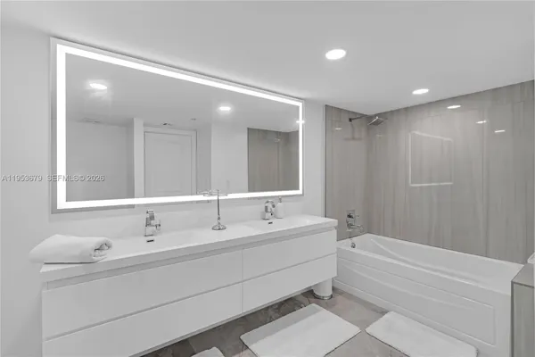 a bathroom with a double vanity sink mirror and bathtub