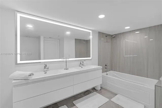 a bathroom with a double vanity sink mirror and bathtub