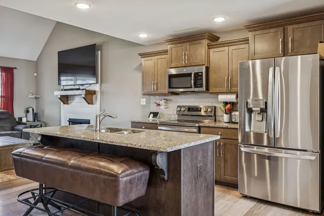 a kitchen with stainless steel appliances granite countertop a refrigerator a stove a sink a oven and a refrigerator