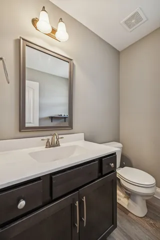 a bathroom with a granite countertop sink a toilet and a mirror
