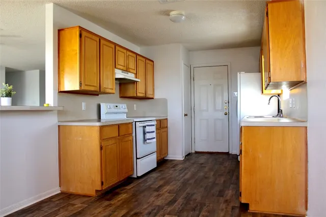 a kitchen with stainless steel appliances granite countertop a refrigerator a stove and a sink with wooden floor