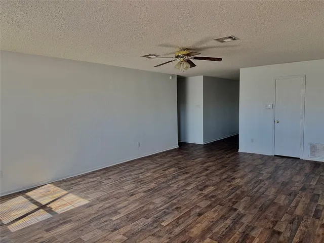 a view of a room with wooden floor and ceiling fan