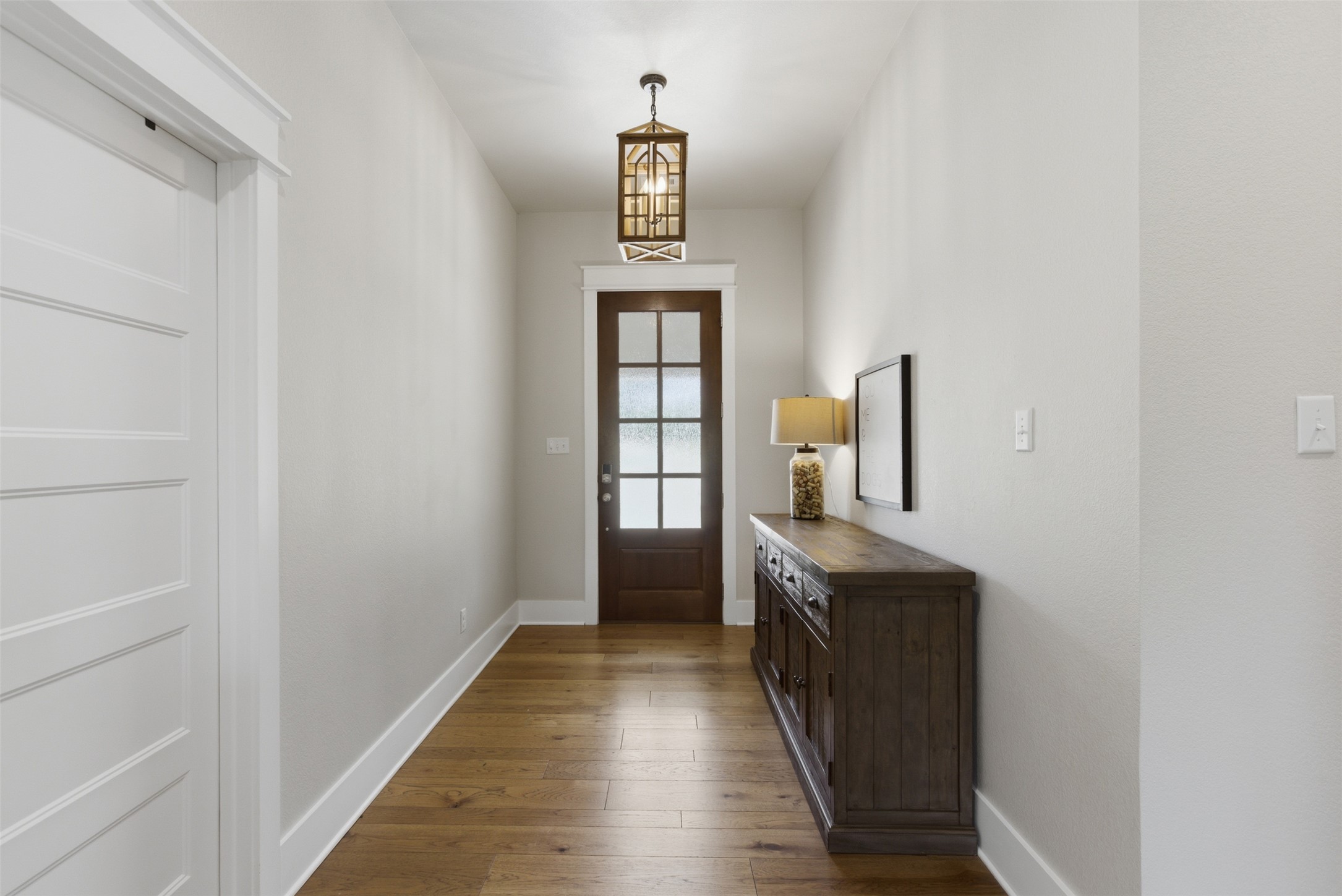 1804 Tanner Loop Taylor, TX 76574 - Photo 21 of 40 The classically elegant entry features wood-flooring, a dark wood-paneled door with frosted glass inserts, and a decorative overhead chandelier.