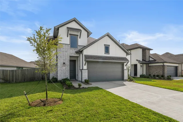 a view of a yard in front of a brick house with a large tree