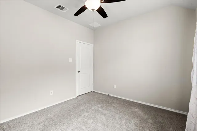 an empty room with a ceiling fan and carpet