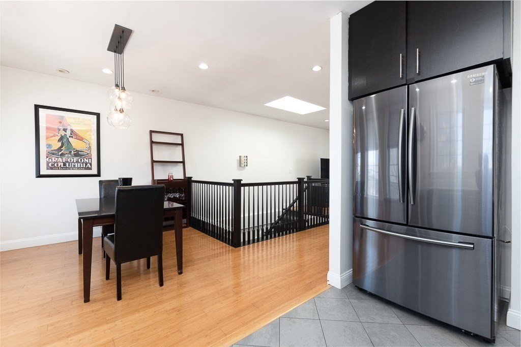 151 G Street, Unit 3 Boston, MA 02127 - Photo 17 of 33 a kitchen with stainless steel appliances granite countertop a refrigerator a stove a dining table and chairs with wooden floor
