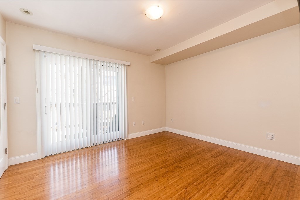 151 G Street, Unit 3 Boston, MA 02127 - Photo 22 of 33 an empty room with wooden floor and windows with curtains