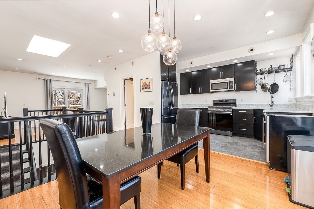 151 G Street, Unit 3 Boston, MA 02127 - Photo 3 of 33 a kitchen with stainless steel appliances kitchen island granite countertop a stove top oven a sink a dining table and chairs with wooden floor
