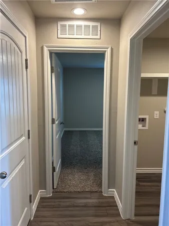 a view of a hallway with wooden floor and a cabinet