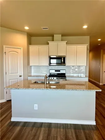 a view of kitchen with stainless steel appliances granite countertop a stove a sink and a microwave