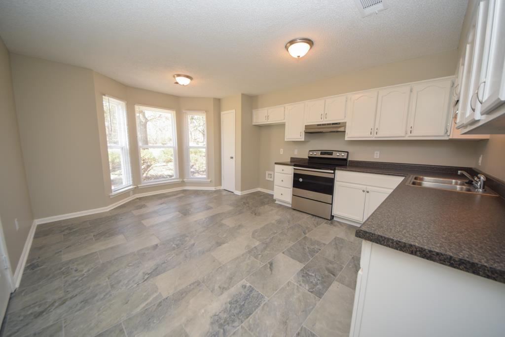 1618 Mathis Road Drummonds, TN 38023 - Photo 3 of 11 Kitchen featuring light tile patterned floors, a textured ceiling, white cabinets, stainless steel range with electric cooktop, and sink