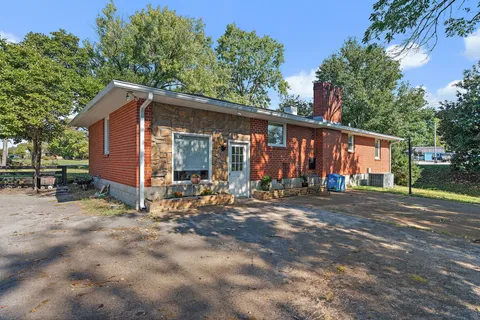 a view of a house with large yard and large tree