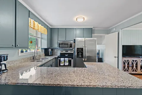 a kitchen with kitchen island granite countertop a sink stove and refrigerator