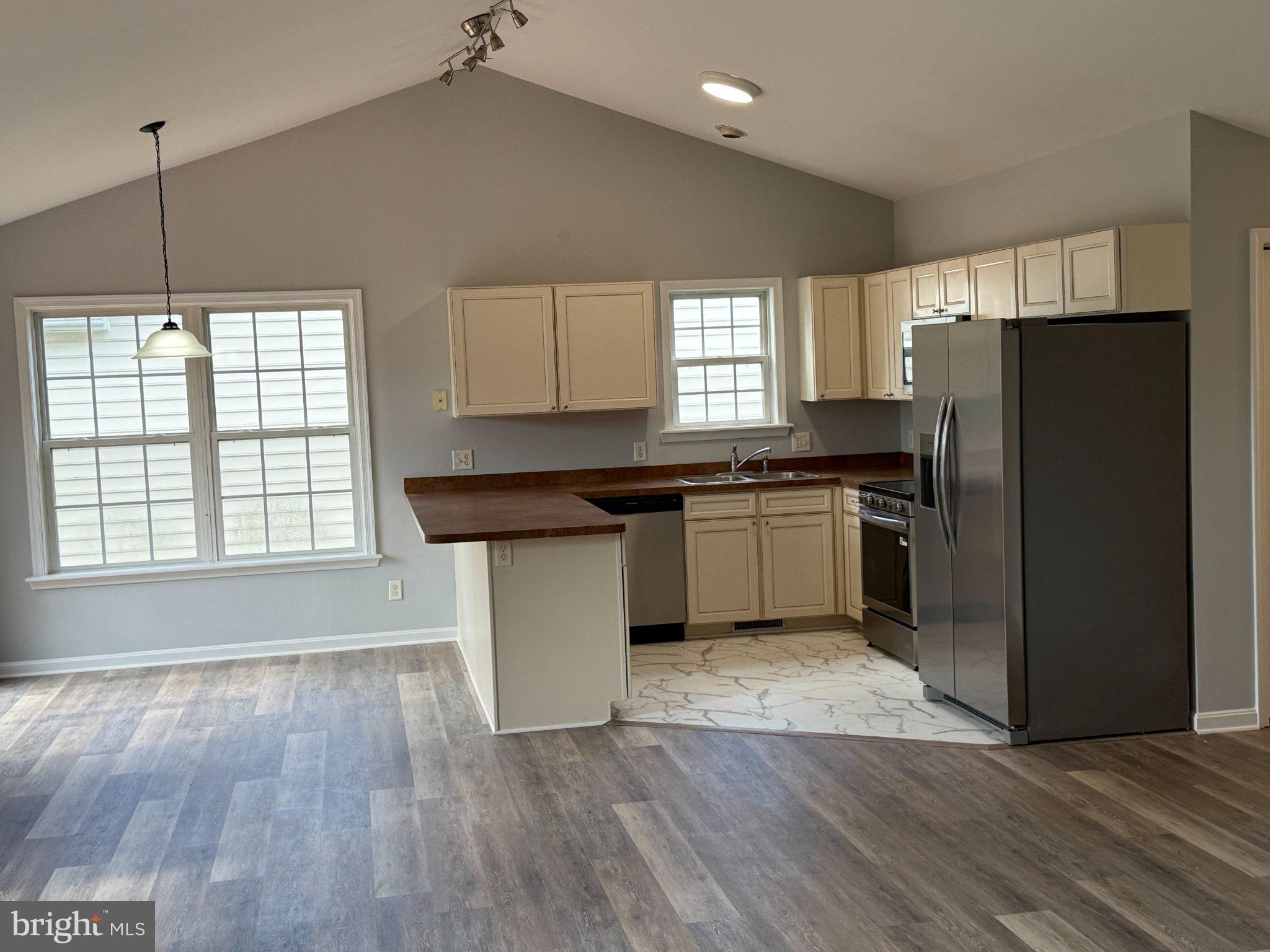 30952 Sandy Ridge Drive Lewes, DE 19958 - Photo 3 of 17 a kitchen with granite countertop a refrigerator a sink dishwasher a stove and white cabinets with wooden floor