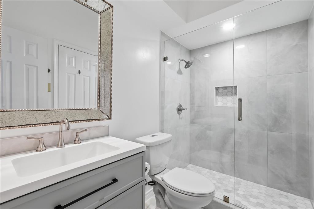 6955 Hawk Road Flower Mound, TX 75022 - Photo 30 of 40 Modern bathroom featuring a frameless glass shower enclosure, large format tile shower surround, hexagon tile shower floor, and a recessed shower niche