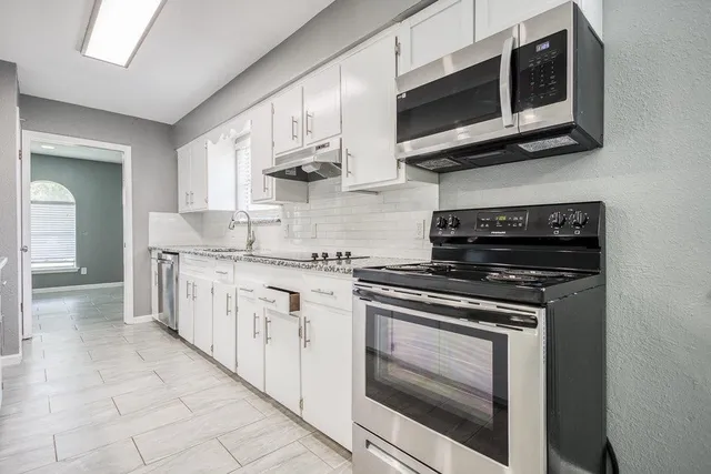 a large kitchen with stainless steel appliances granite countertop a stove and a sink