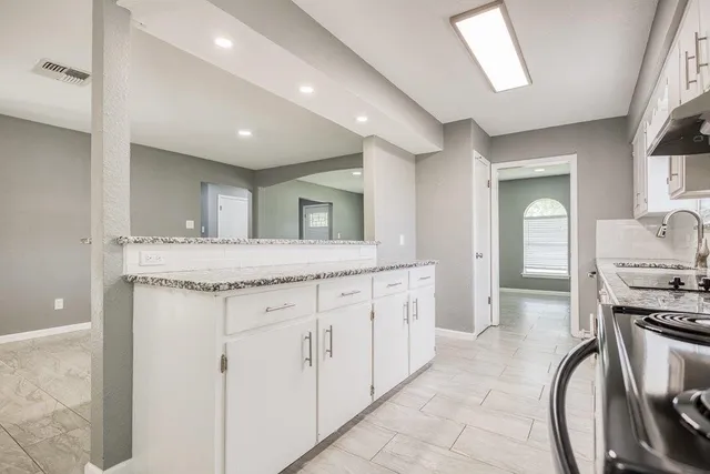 a kitchen with stainless steel appliances granite countertop white cabinets a sink a stove a window and white appliances