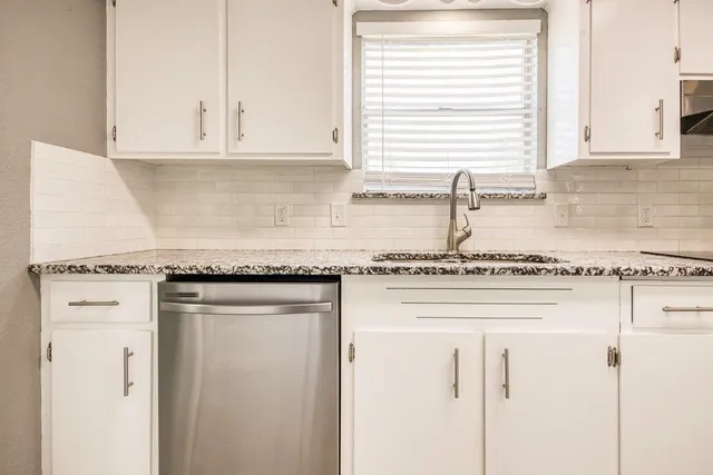 a large kitchen with granite countertop a sink and cabinets