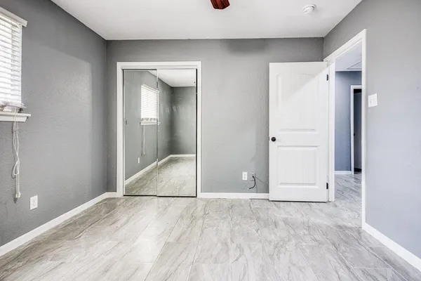 an empty room with windows and chandelier fan