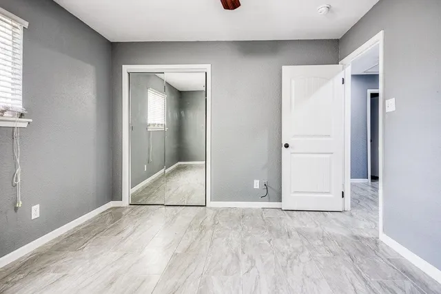 an empty room with windows and chandelier fan