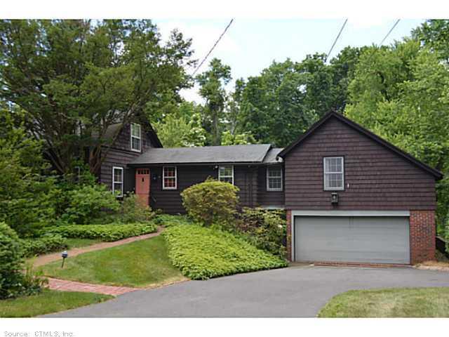 a view of a house that has a small yard and large trees
