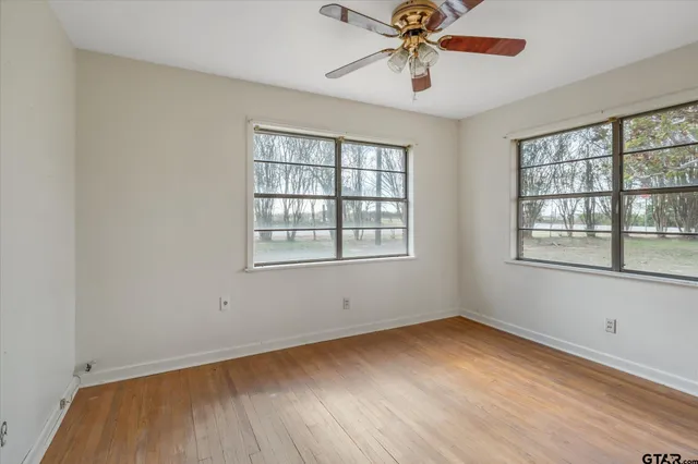 a view of an empty room with wooden floor and window