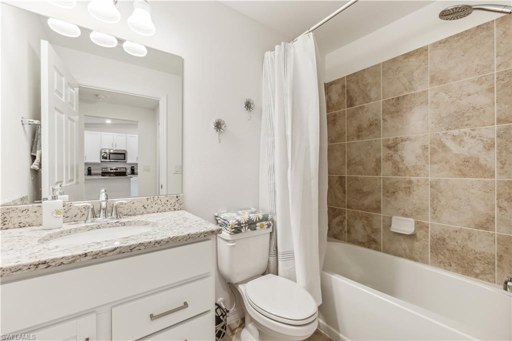 43051 Greenway Boulevard, Unit 822 Babcock Ranch, FL 33982 - Photo 14 of 16 a bathroom with a granite countertop sink a toilet and bathtub