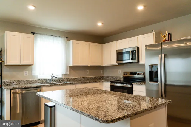 a kitchen with stainless steel appliances granite countertop a sink a stove and a refrigerator