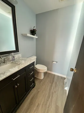 a bathroom with a granite countertop sink a toilet a mirror and shower