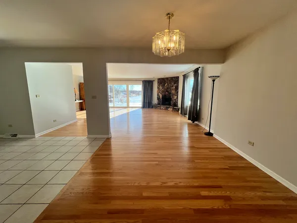 a view of an empty room and kitchen with a chandelier