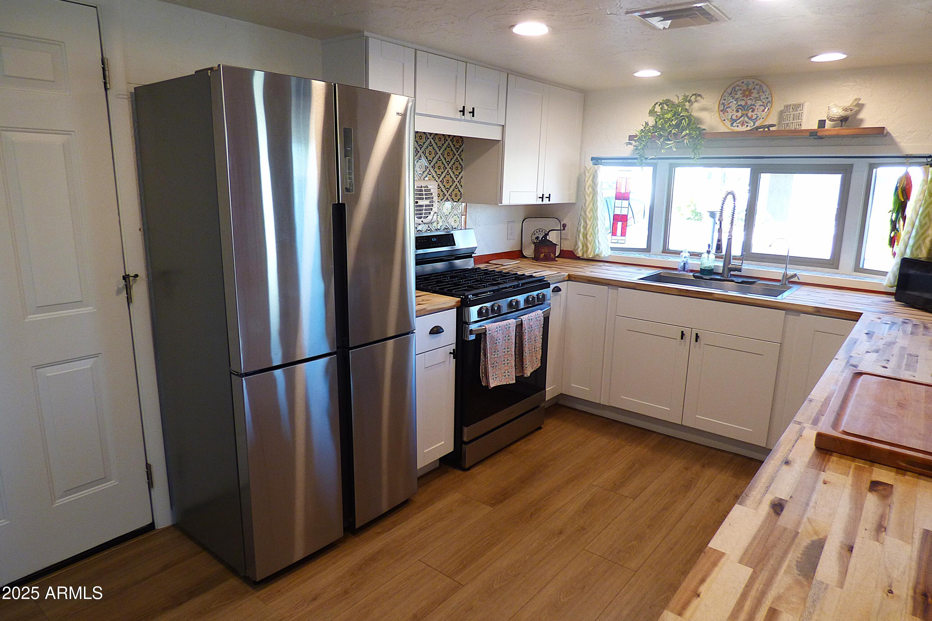 6700 East Thomas Road, Unit 34 Scottsdale, AZ 85251 - Photo 5 of 69 a kitchen with stainless steel appliances granite countertop a refrigerator a sink dishwasher a stove and white countertops with wooden floor