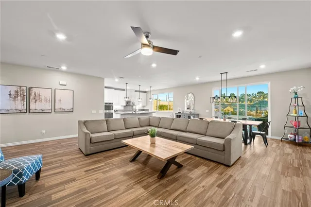 a living room with furniture kitchen view and a wooden floor