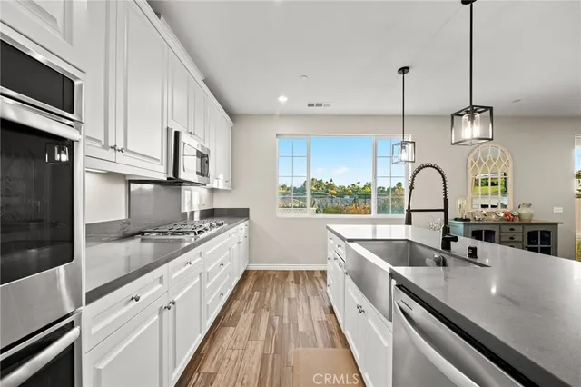 a kitchen with granite countertop a sink a counter space appliances and cabinets