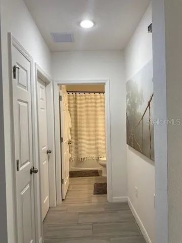 a view of a hallway with wooden floor and cabinet