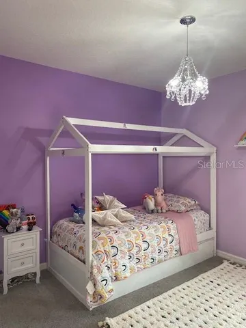 a bedroom with a bed chandelier and a window