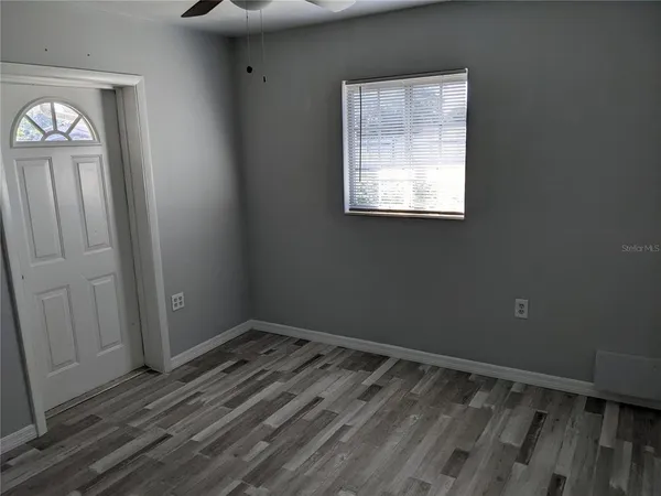 a view of empty room with wooden floor and fan