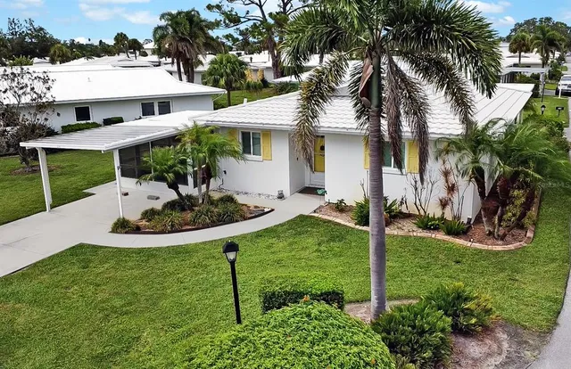 a view of a white house with a yard patio and swimming pool